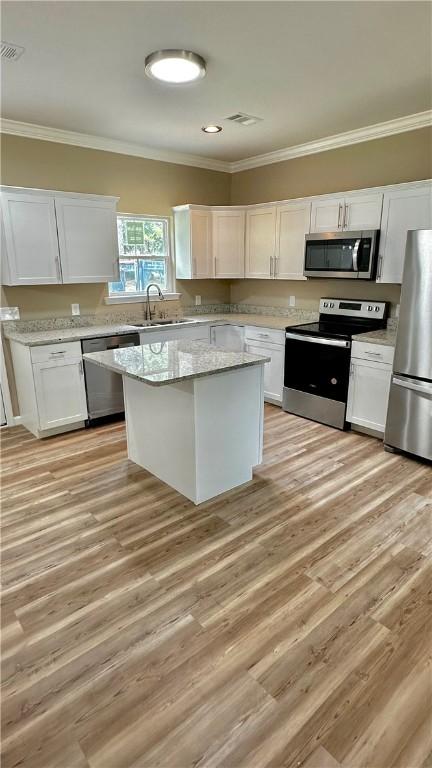 kitchen with light stone countertops, appliances with stainless steel finishes, light hardwood / wood-style flooring, and white cabinetry