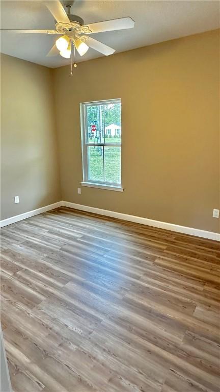 empty room with ceiling fan and hardwood / wood-style floors