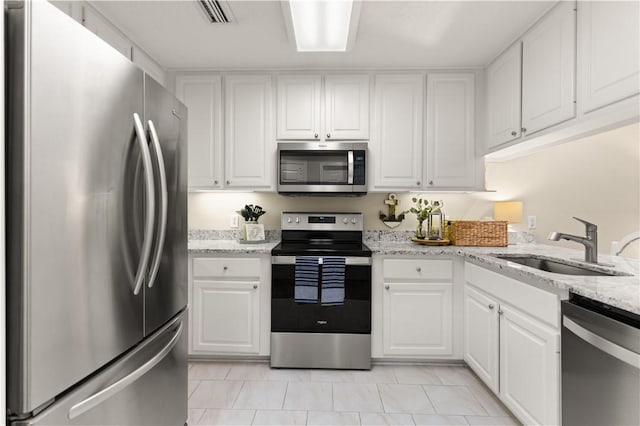 kitchen featuring white cabinetry, stainless steel appliances, light stone countertops, and sink