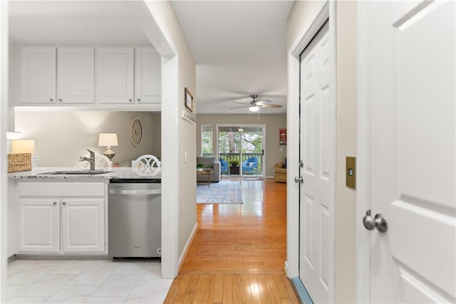 kitchen featuring sink, stainless steel dishwasher, white cabinets, and light stone countertops