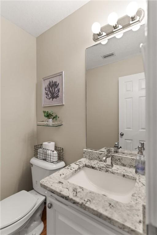 bathroom featuring vanity, an inviting chandelier, and toilet