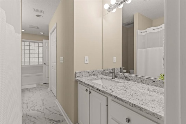 bathroom with vanity, toilet, and a textured ceiling