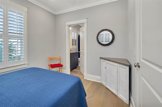 bedroom featuring light wood-style flooring, ensuite bath, crown molding, and baseboards