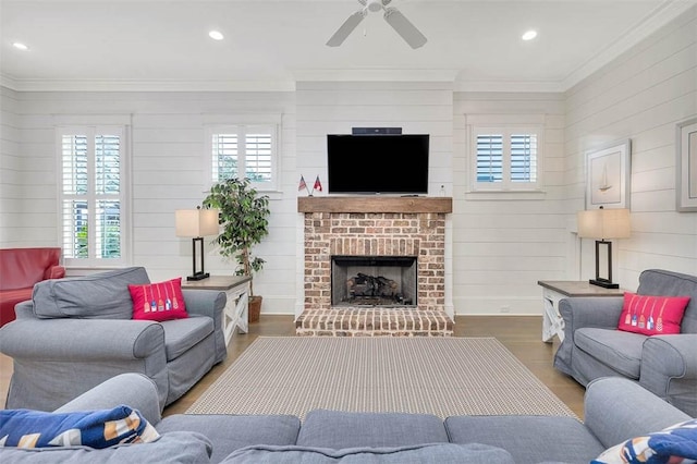 living area with a brick fireplace, wood finished floors, and ornamental molding