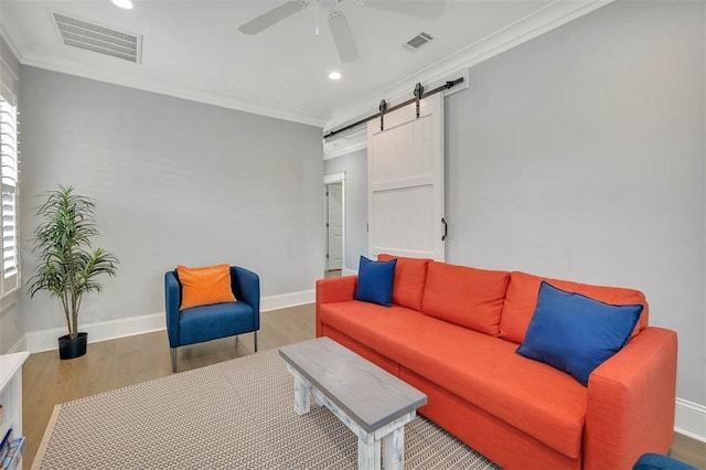 living room featuring visible vents, wood finished floors, a barn door, and ornamental molding