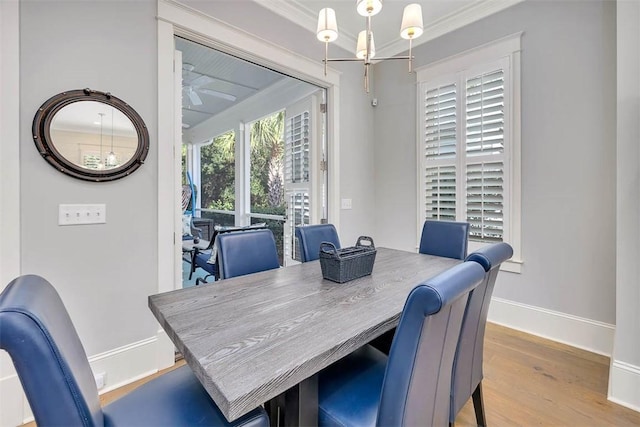 dining space with ceiling fan with notable chandelier, wood finished floors, baseboards, and ornamental molding