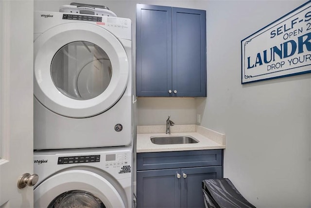 laundry area featuring a sink, stacked washer / drying machine, and cabinet space