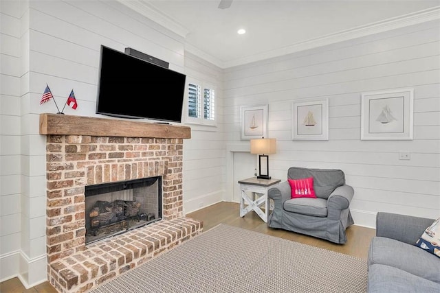 living area with wood finished floors, baseboards, a fireplace, recessed lighting, and crown molding