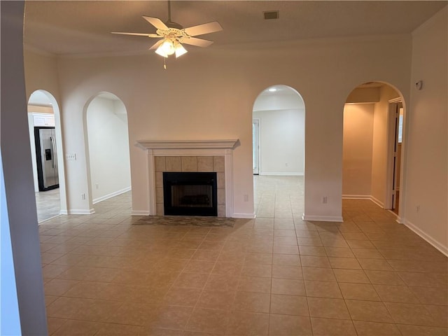 208 Stafford Ave, Brunswick, GA 31520 - unfurnished living room with ceiling fan, crown molding, light tile patterned floors, a tiled fireplace, and arched walkways