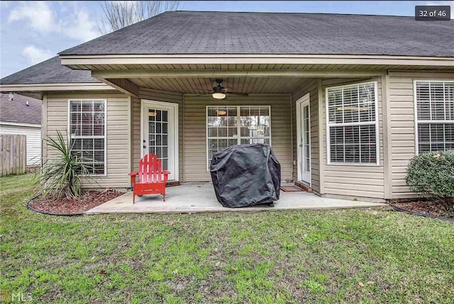 rear view of property with fence, roof with shingles, a patio, a yard, and a ceiling fan