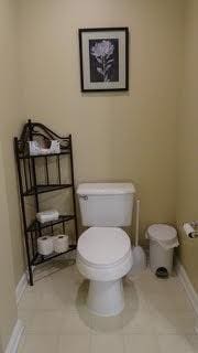 half bathroom featuring tile patterned flooring, toilet, and baseboards