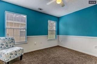 unfurnished room with carpet flooring, visible vents, a ceiling fan, and a wainscoted wall