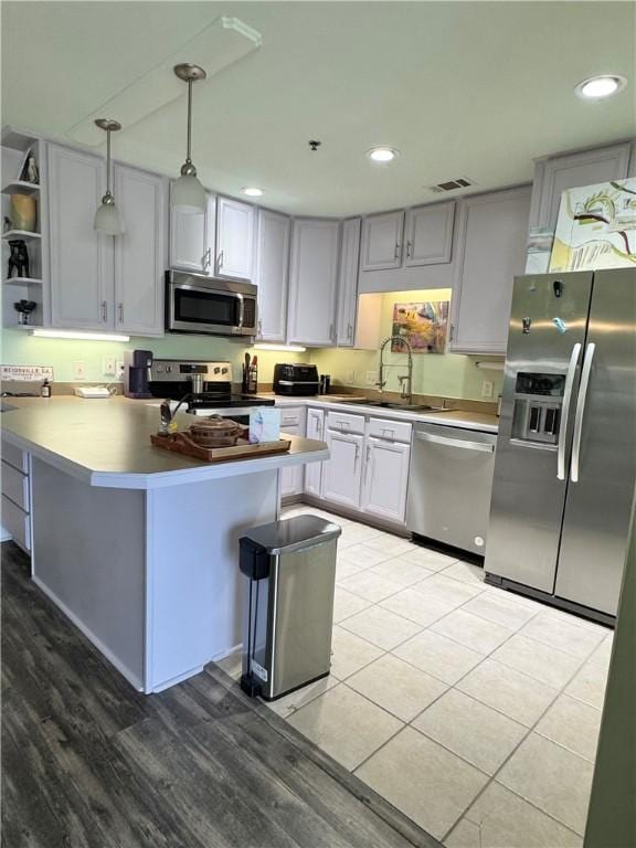 91 Screven St Unit 105, Darien, GA 31305 - kitchen with appliances with stainless steel finishes, a sink, light wood-type flooring, a peninsula, and hanging light fixtures