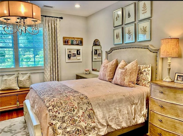 bedroom with wood-type flooring and an inviting chandelier