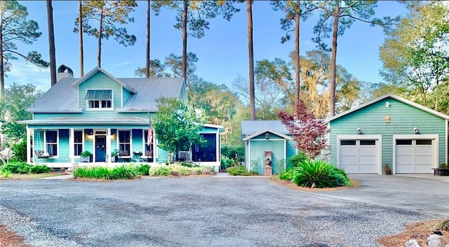 view of front facade featuring a porch, a garage, and an outbuilding