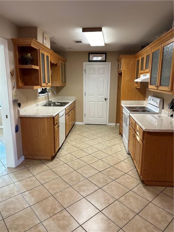 kitchen with light stone countertops, light tile patterned floors, white appliances, and sink