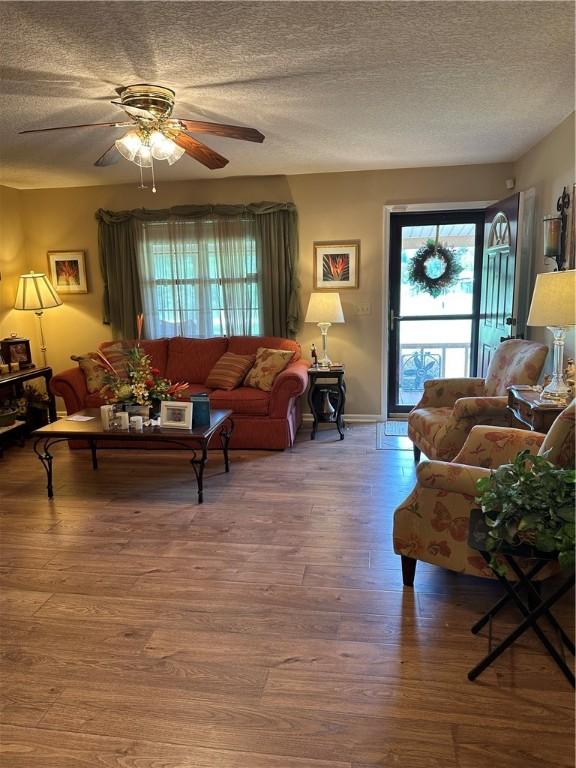 living room with hardwood / wood-style flooring, ceiling fan, and a textured ceiling