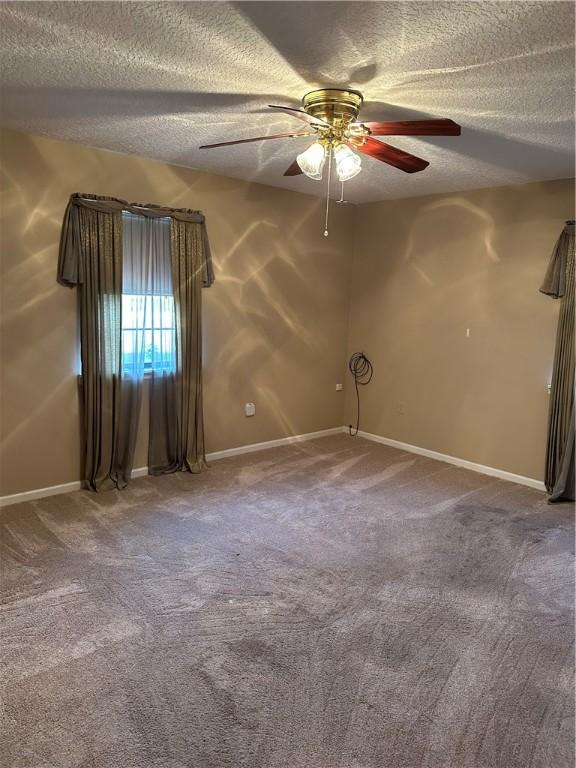 carpeted empty room featuring ceiling fan and a textured ceiling