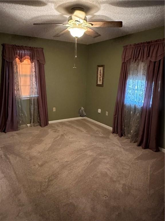 carpeted empty room featuring ceiling fan and a textured ceiling