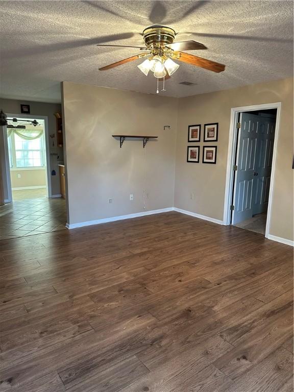 empty room featuring a textured ceiling, ceiling fan, and dark hardwood / wood-style floors