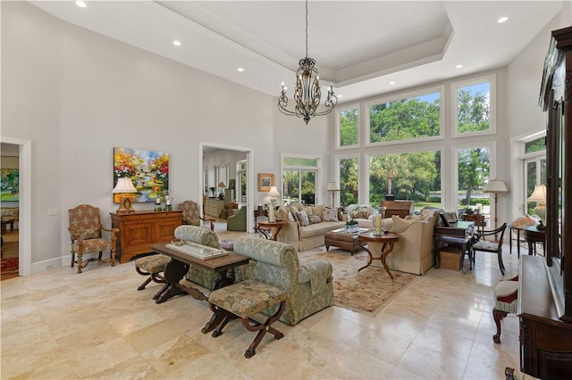 living room with a chandelier, a high ceiling, a raised ceiling, and a wealth of natural light