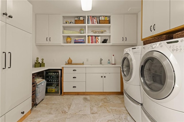 laundry area with washer and clothes dryer, cabinets, sink, and beverage cooler