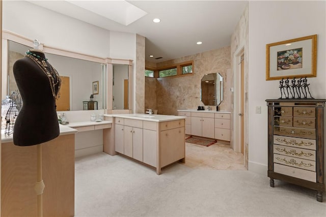 bathroom featuring vanity, a healthy amount of sunlight, tile walls, and a skylight