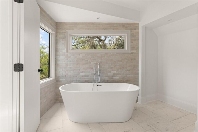 full bath featuring a freestanding bath and baseboards