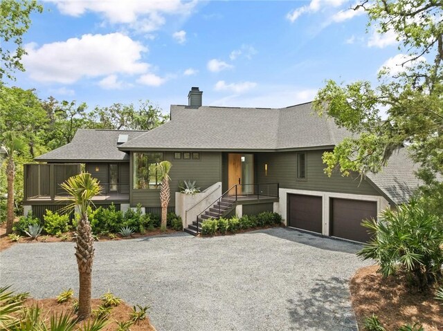 view of front of house featuring an attached garage, a chimney, aphalt driveway, and roof with shingles