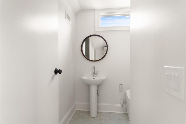 half bath featuring baseboards, toilet, and visible vents