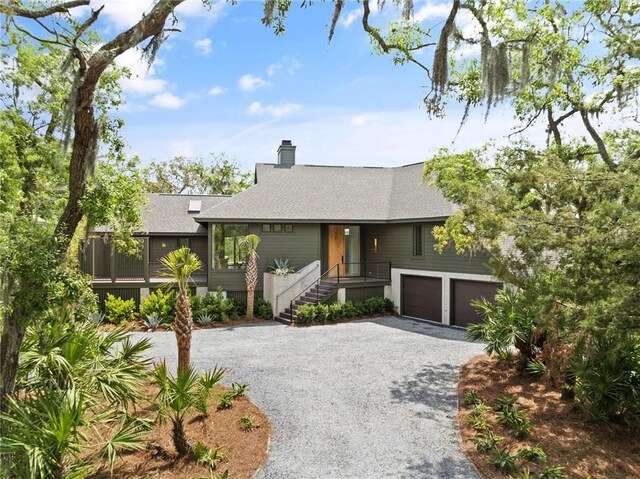 ranch-style house featuring a chimney, driveway, and a shingled roof