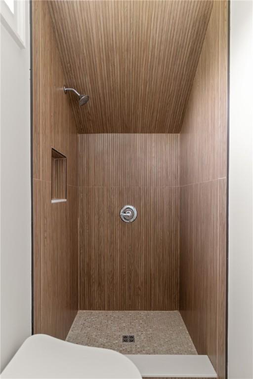 bathroom with toilet, wooden ceiling, and tiled shower