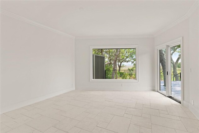spare room featuring baseboards, ornamental molding, and stone tile floors