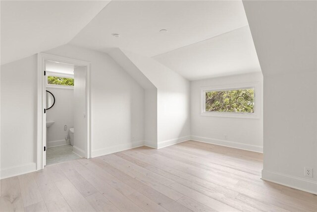 bonus room with light wood-type flooring and lofted ceiling