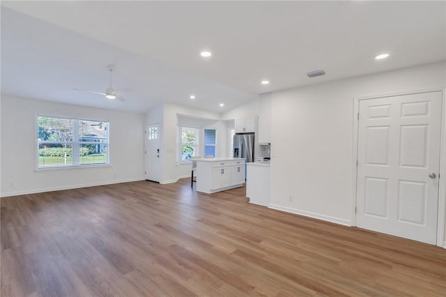 unfurnished living room with light hardwood / wood-style floors, ceiling fan, and lofted ceiling