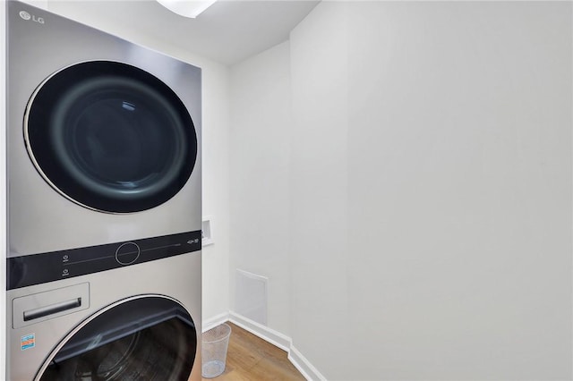 laundry room with hardwood / wood-style floors and stacked washing maching and dryer