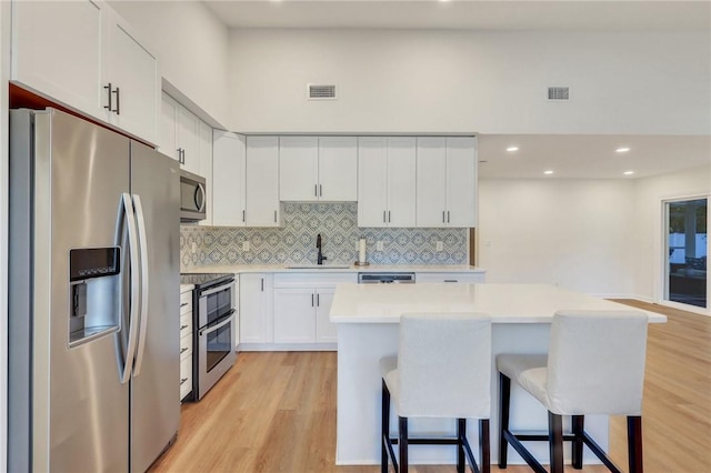 kitchen with white cabinets, a center island, stainless steel appliances, and a breakfast bar area