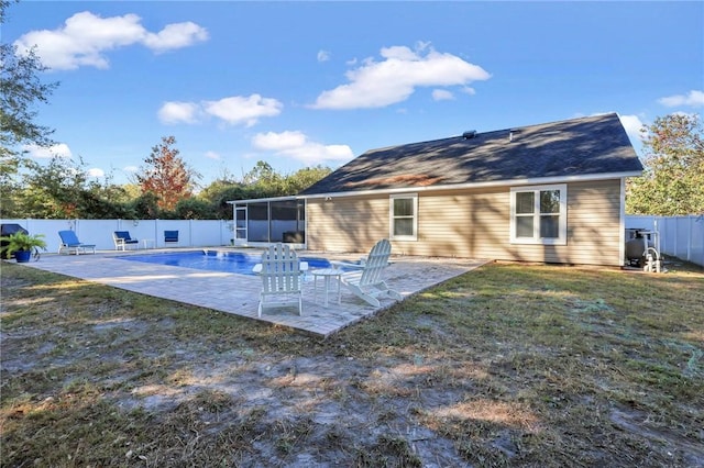 rear view of property featuring a fenced in pool, a lawn, a patio area, and a sunroom