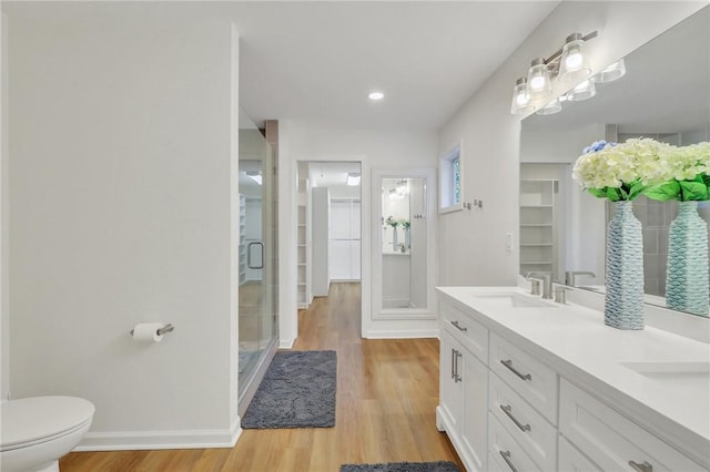 bathroom featuring toilet, vanity, a shower with shower door, and hardwood / wood-style flooring