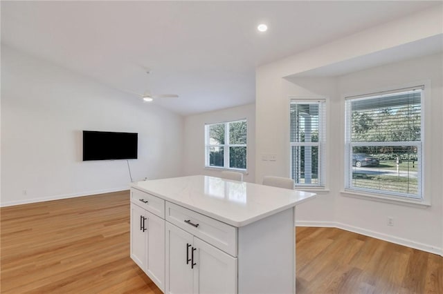 kitchen with a center island, light hardwood / wood-style flooring, white cabinets, and a healthy amount of sunlight