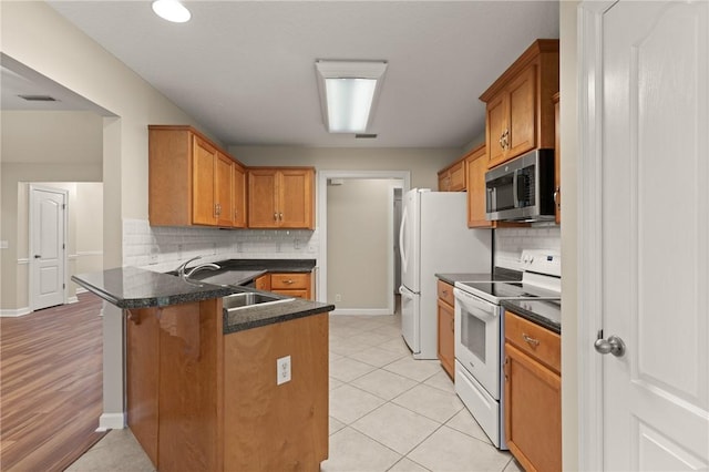 172 Autumns Ridge Ct, Brunswick, GA 31525 - kitchen featuring stainless steel microwave, white range with electric stovetop, a peninsula, dark countertops, and brown cabinets