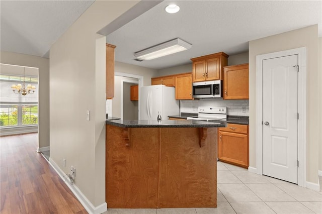 172 Autumns Ridge Ct, Brunswick, GA 31525 - kitchen with white appliances, a chandelier, backsplash, a peninsula, and brown cabinets