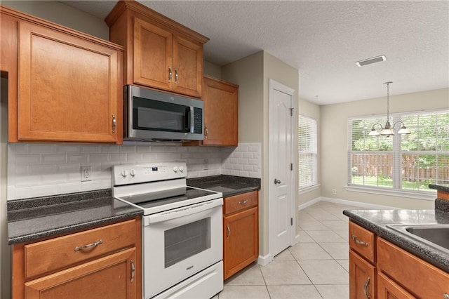 172 Autumns Ridge Ct, Brunswick, GA 31525 - kitchen featuring white electric range oven, stainless steel microwave, light tile patterned floors, dark countertops, and decorative backsplash