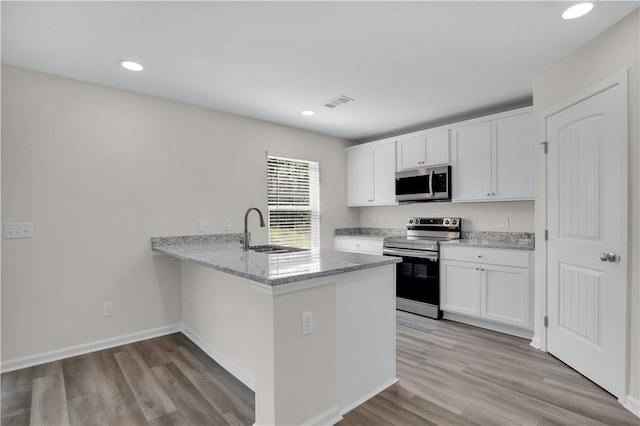 kitchen featuring light hardwood / wood-style floors, white cabinetry, kitchen peninsula, and appliances with stainless steel finishes