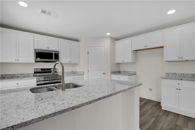 kitchen featuring light stone countertops, sink, appliances with stainless steel finishes, white cabinets, and hardwood / wood-style flooring