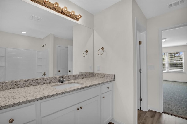 bathroom with hardwood / wood-style floors, vanity, and walk in shower