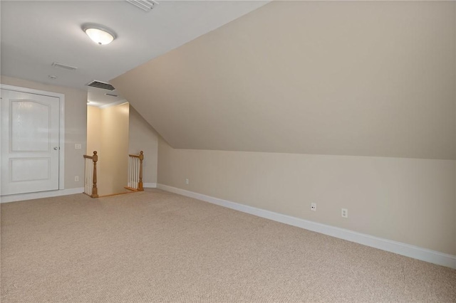 additional living space with light colored carpet, baseboards, lofted ceiling, and visible vents