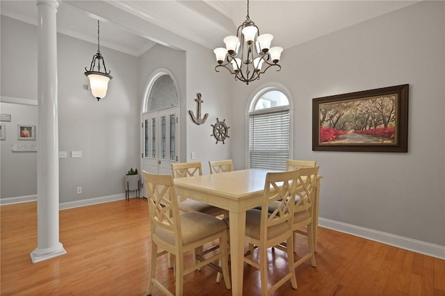 dining room with an inviting chandelier, baseboards, light wood-type flooring, ornate columns, and ornamental molding