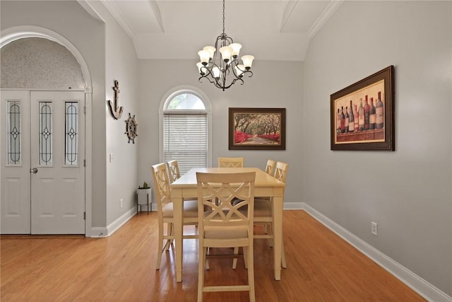 dining room featuring light wood-style floors, arched walkways, baseboards, and an inviting chandelier