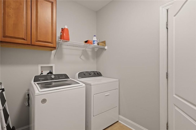 clothes washing area with cabinet space, baseboards, and washer and dryer